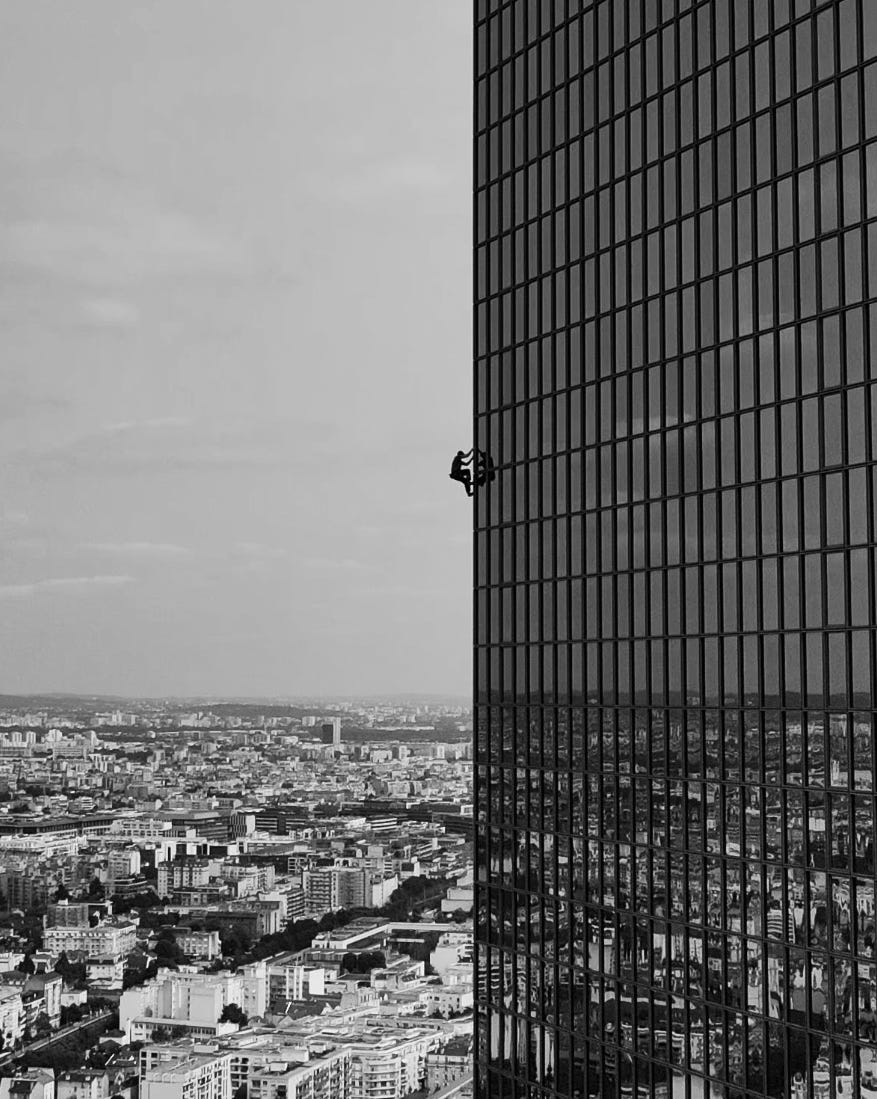 person scaling the side of a tall building in an urban setting