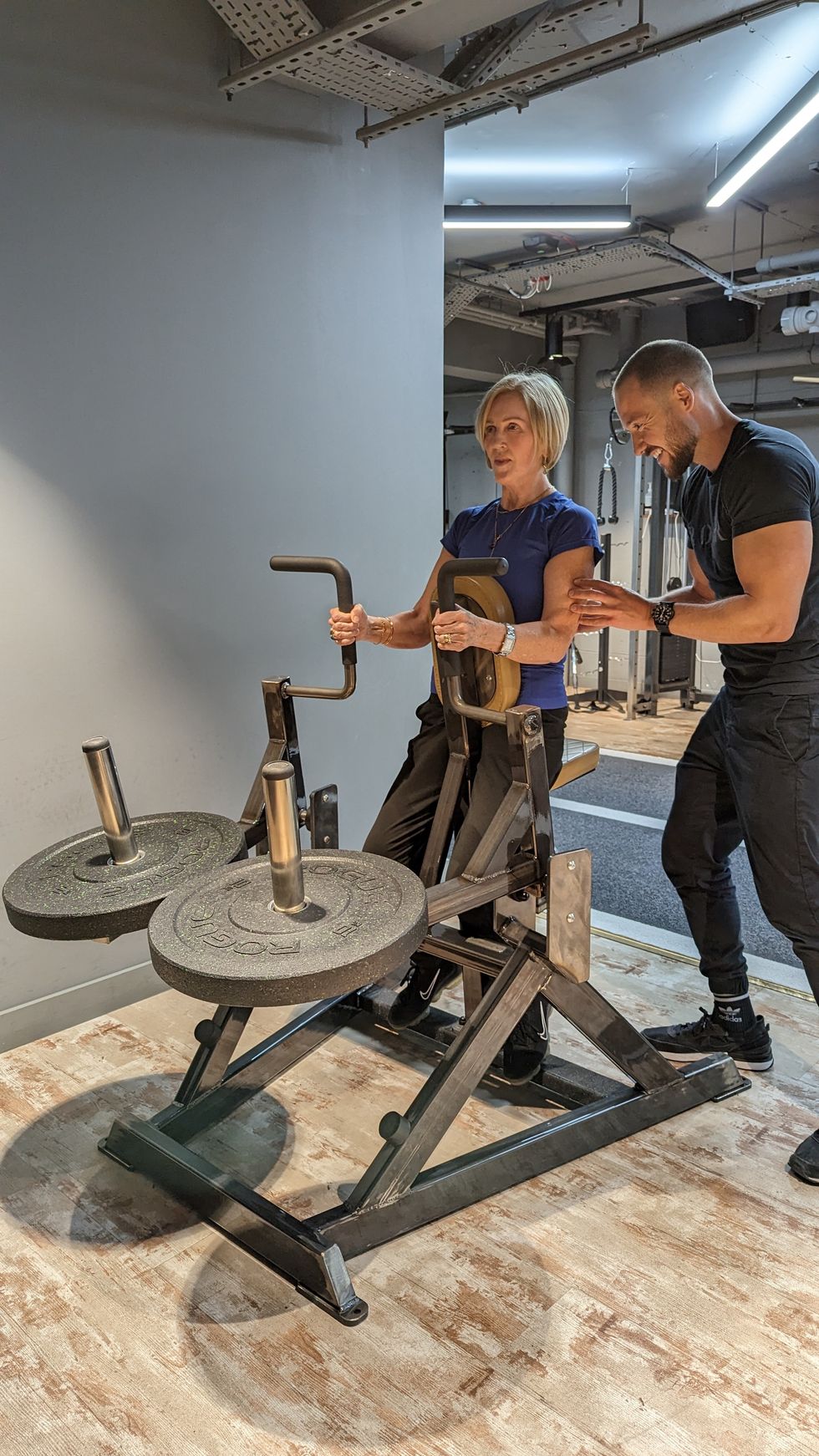 woman using gym equipment with personal trainer