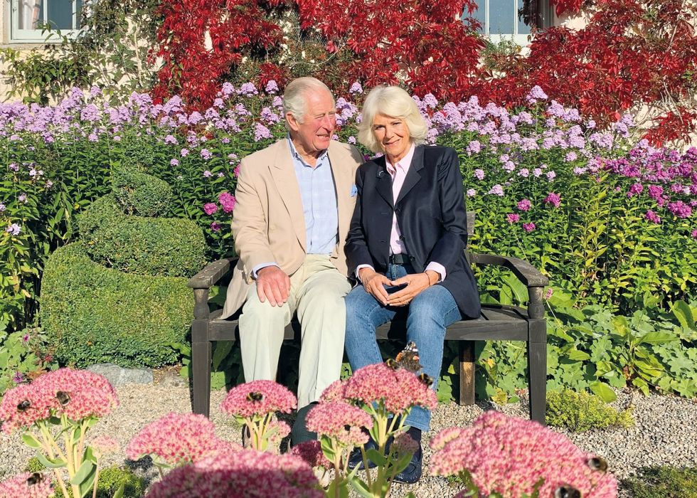charles and camilla sit on a bench in a garden