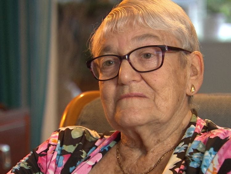elderly person wearing glasses and seated in an indoor environment