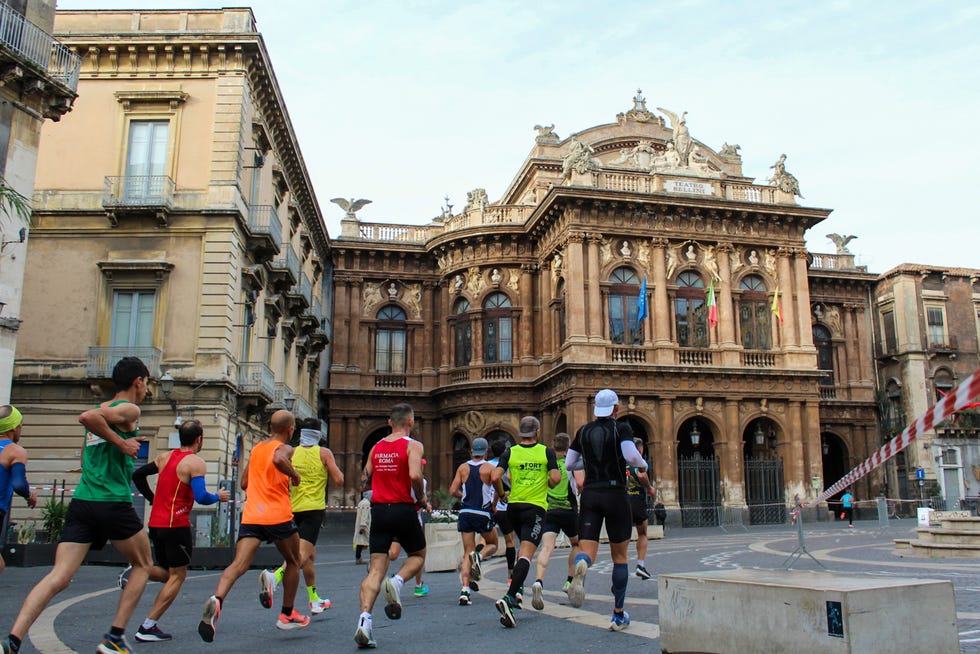 a group of people running in a street in front of a building