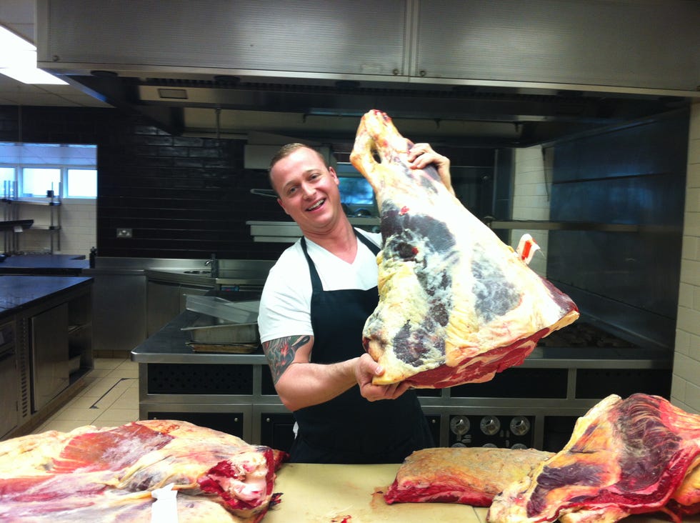 a person holding a large piece of meat in a kitchen