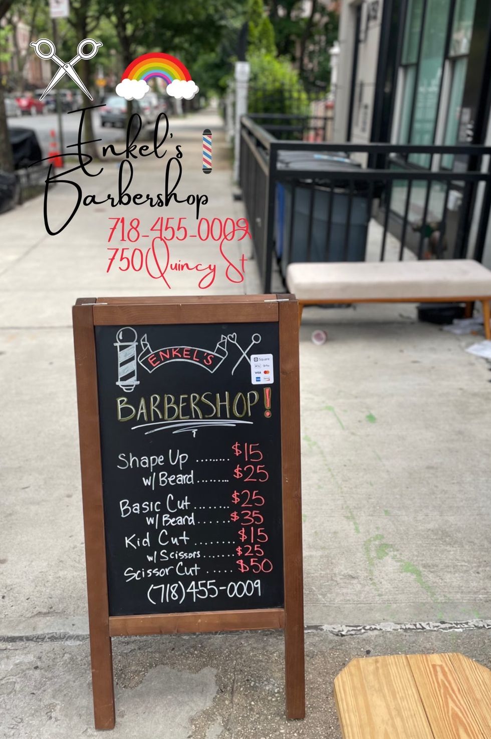 a street placard outside of enkel's barbershop displaying prices for haircuts