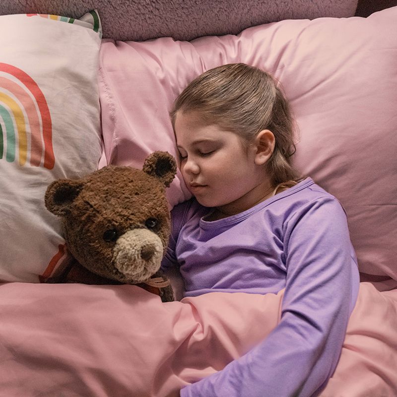 a girl sleeping with a teddy bear