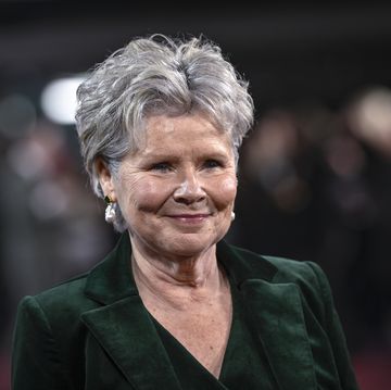 imelda staunton, wearing a green suit, smiles as she attends a red carpet event