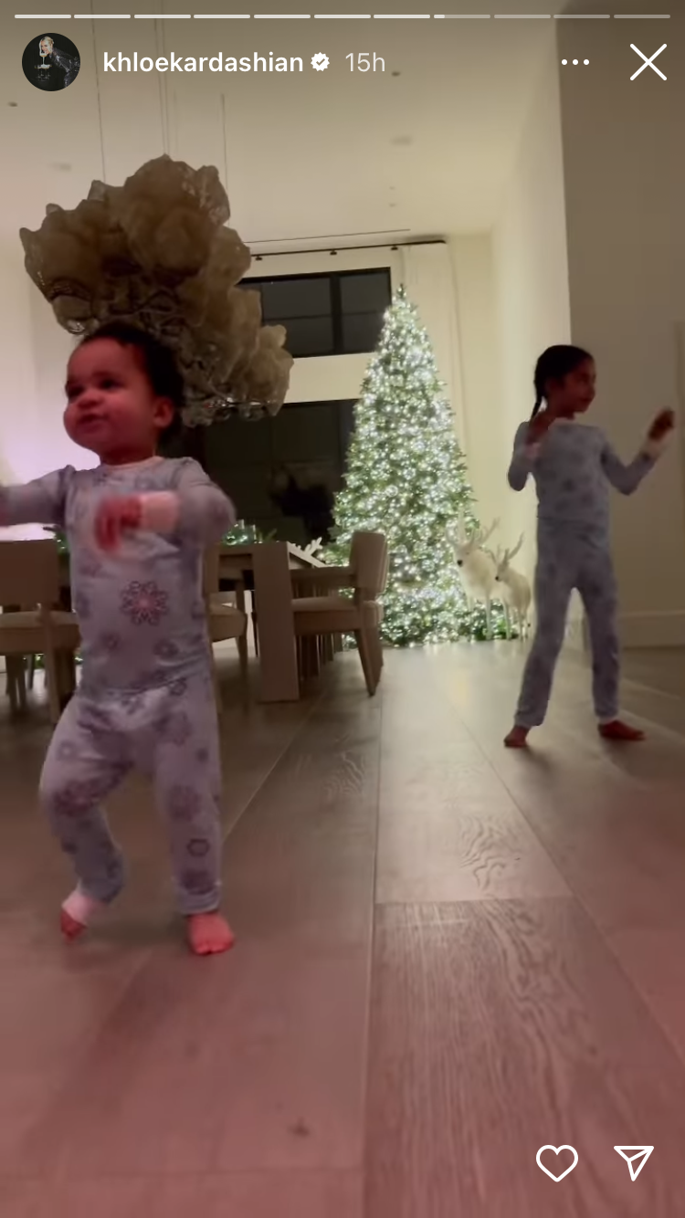 un par de niños bailando en una habitación decorada con un árbol de navidad