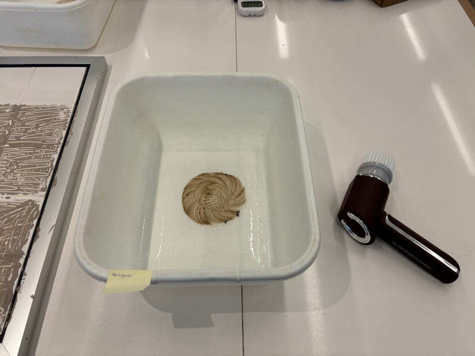 a dish basin with a circle of clay mask in the middle and a electric scrubber beside the basin
