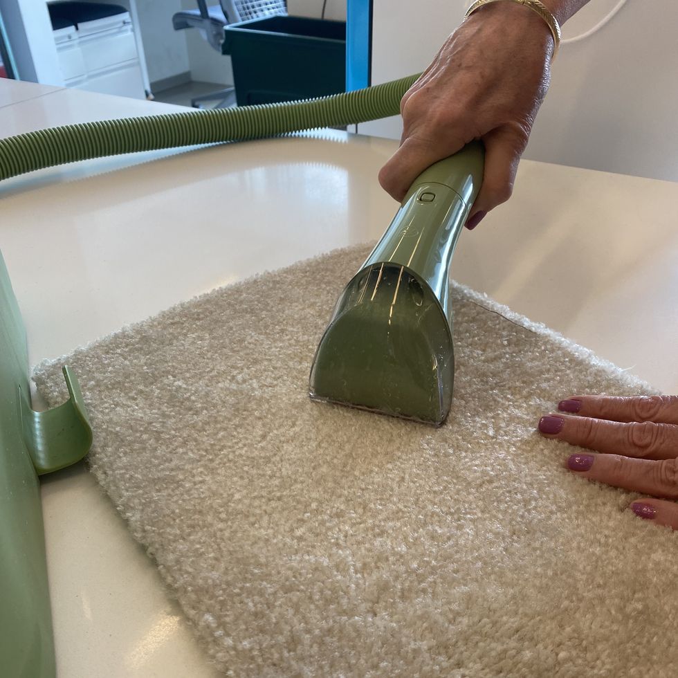bissell little green carpet cleaner hand nozzle extracting water and stain from a carpet during testing