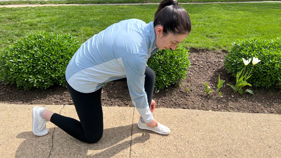 a woman bending down to tie a shoe