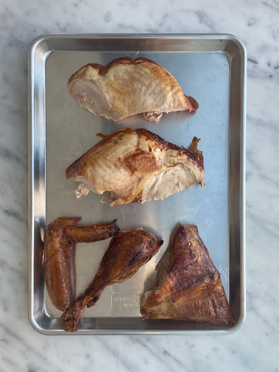 whole roasted turkey in a metal roasting pan broken up into pieces