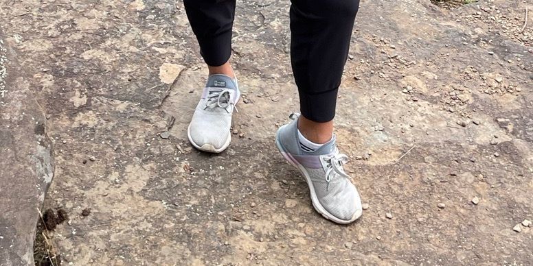 a person's legs and feet modeling new balance sneakers against a rocky background