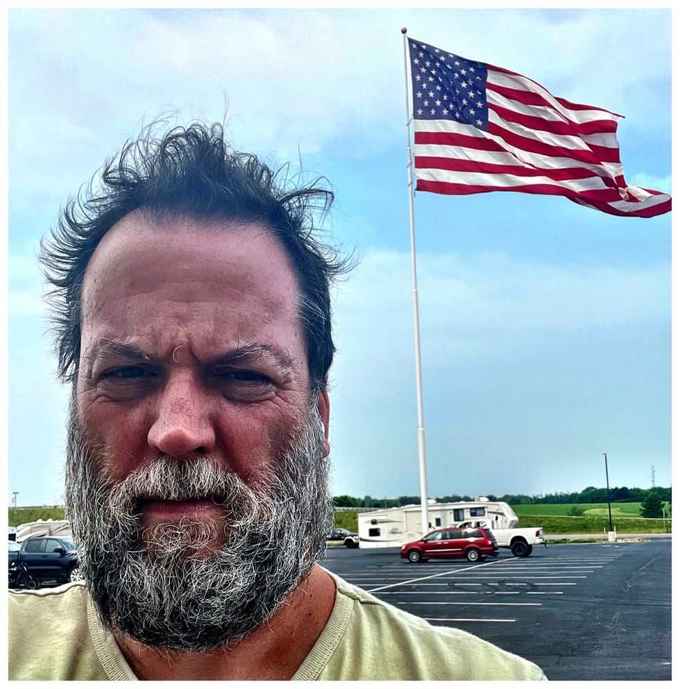 man standing in front of a flag