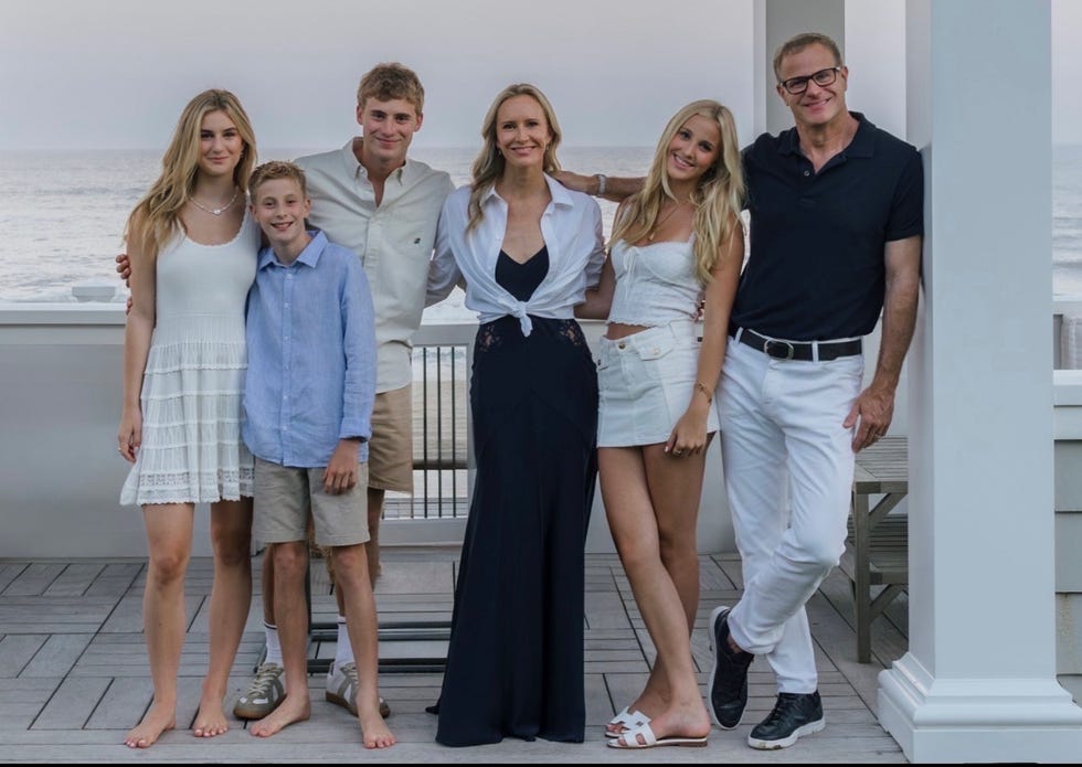 group of six people posing together outdoors near the beach