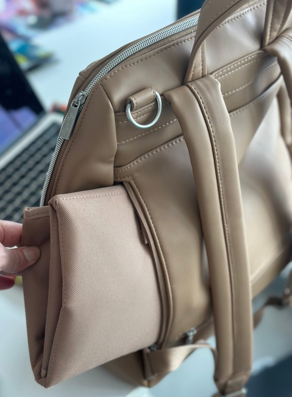 a lab tester pulls the changing pad out of the back of an itzy ritzy backpack diaper bag, part of a good housekeeping list of the best backpack diaper bags