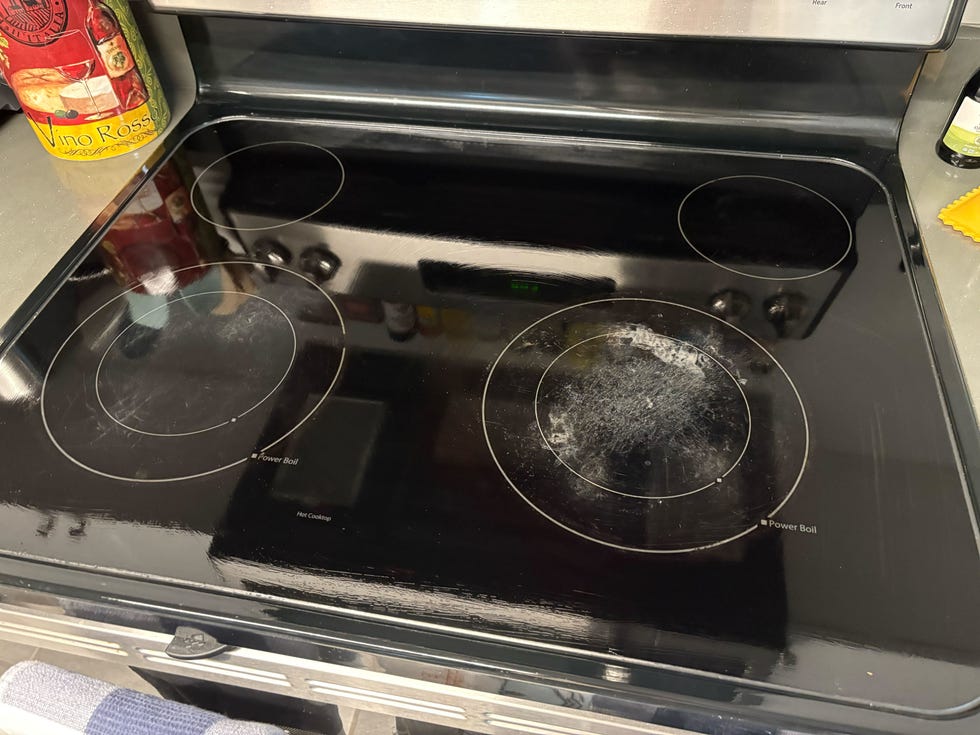 cooktop with induction heating elements and a visible wine bottle