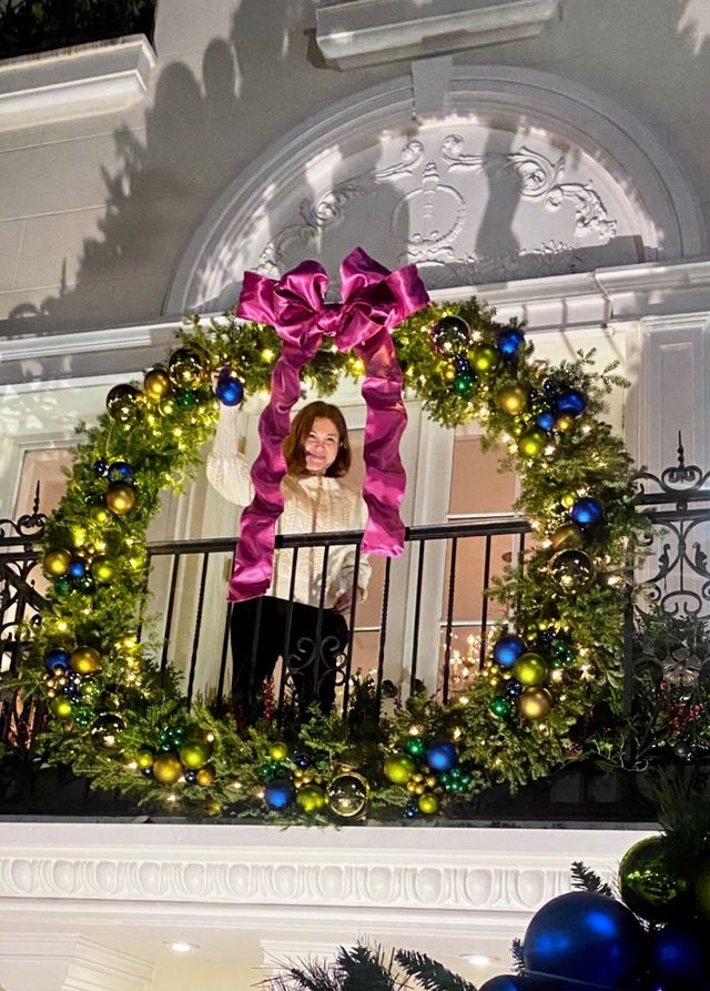 a decorator hanging a wreath from a porch
