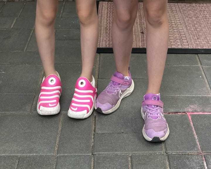 two girls wear pink nike sneakers, a good housekeeping pick for best kids walking dhoes