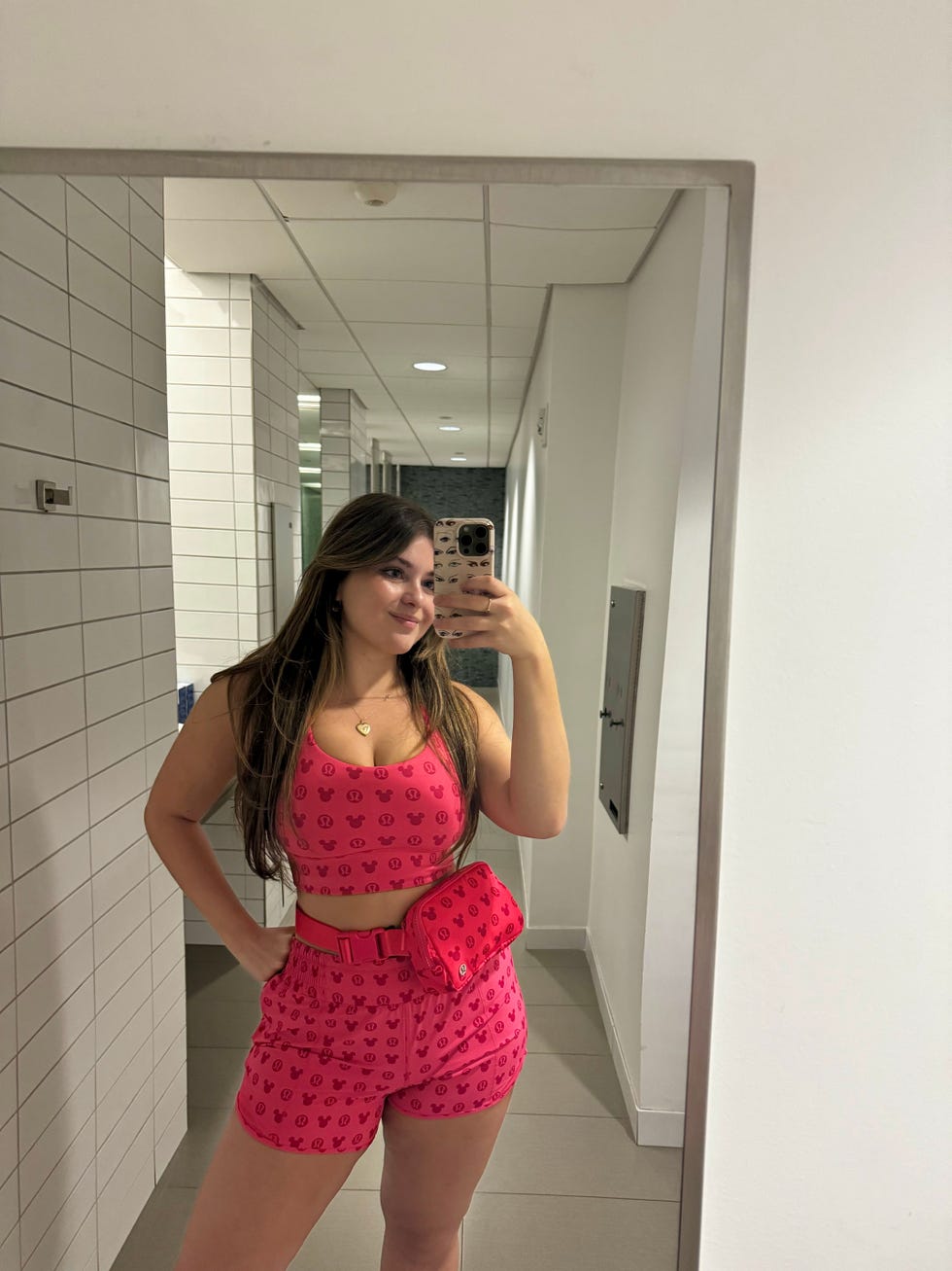 person wearing a pink matching outfit with a belt bag in a restroom setting
