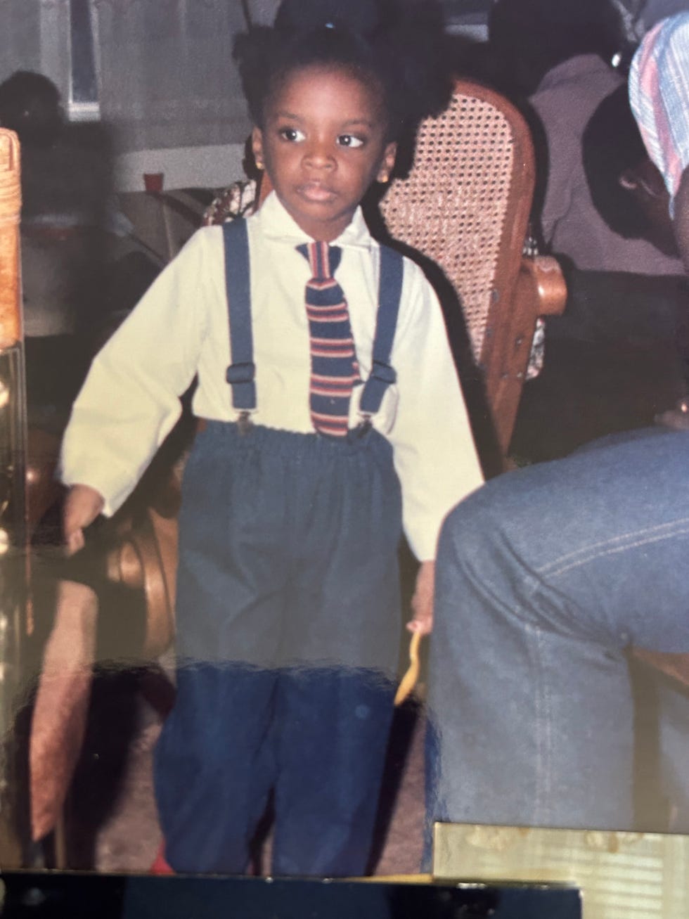 a child wearing a formal outfit stands amid a gathering