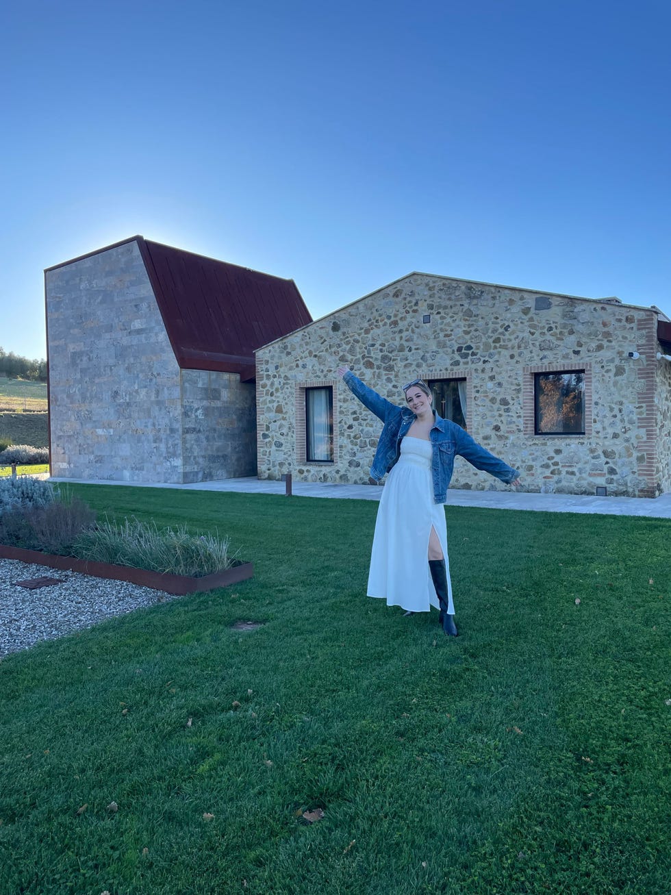 a person in a white dress standing in front of a stone building