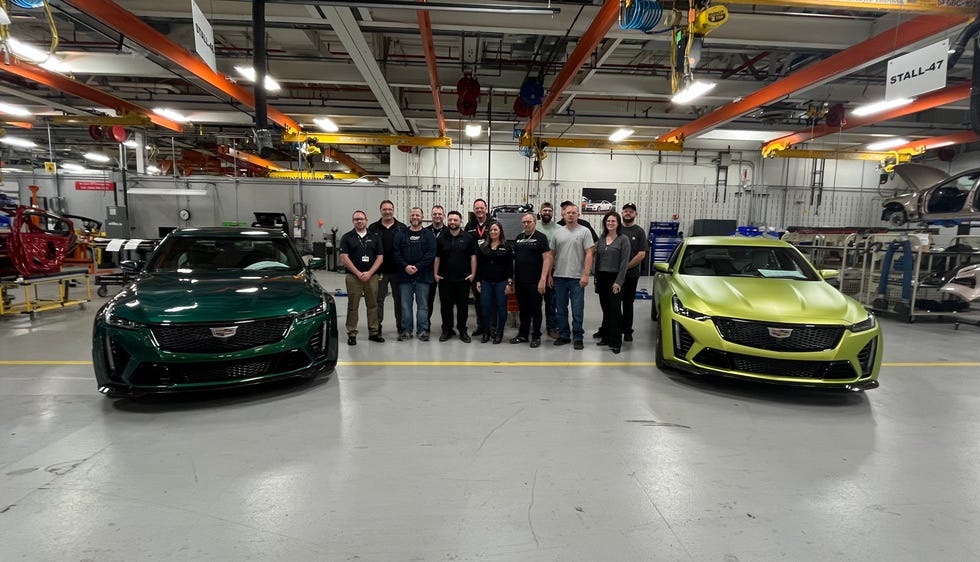 a group of people standing next to a couple of cars in a garage