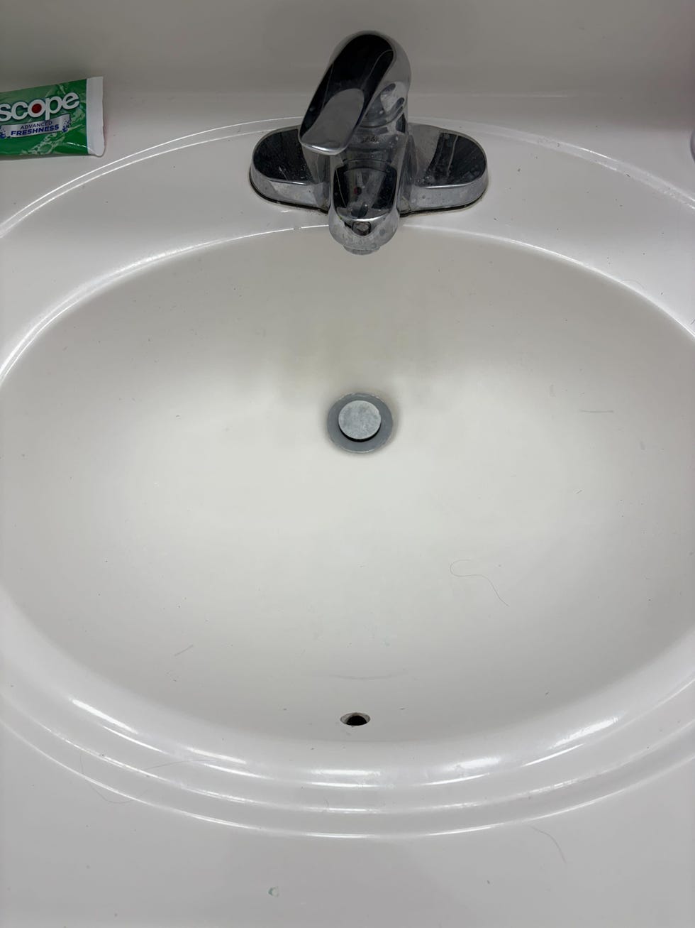 bathroom sink with a chrome faucet and a tube of mouthwash