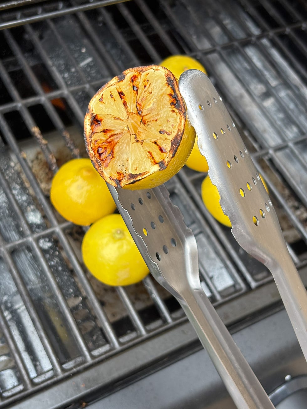 grilled lemon with tongs on a barbecue grill