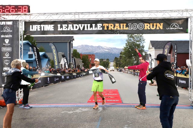 a runner breaks the tape at the finish line of a race