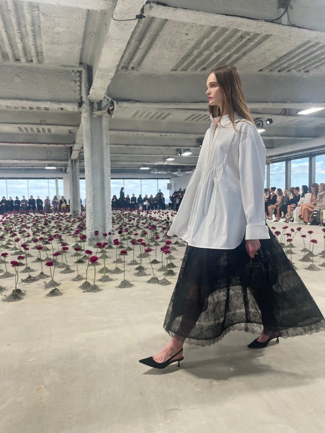 fashion model walking amidst an artistic display of roses during a runway show