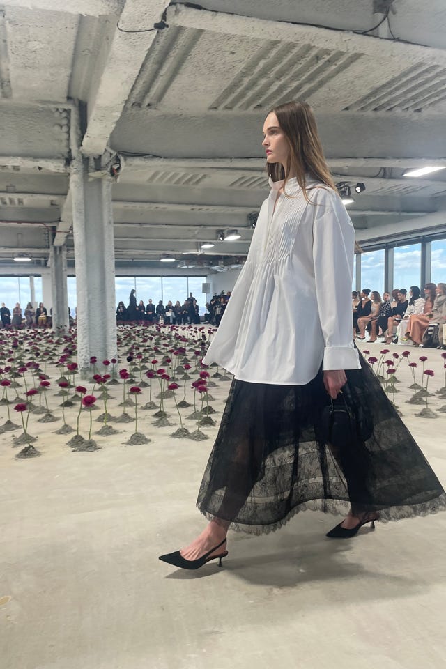 fashion model walking amidst an artistic display of roses during a runway show fashion model walking amidst an artistic display of roses during a runway show