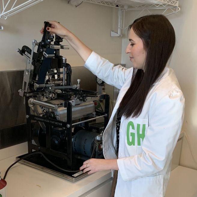 a good housekeeping lab analyst is loading samples into a machine to test abrasion resistance at the good housekeeping institute to find the best laptop bags for women