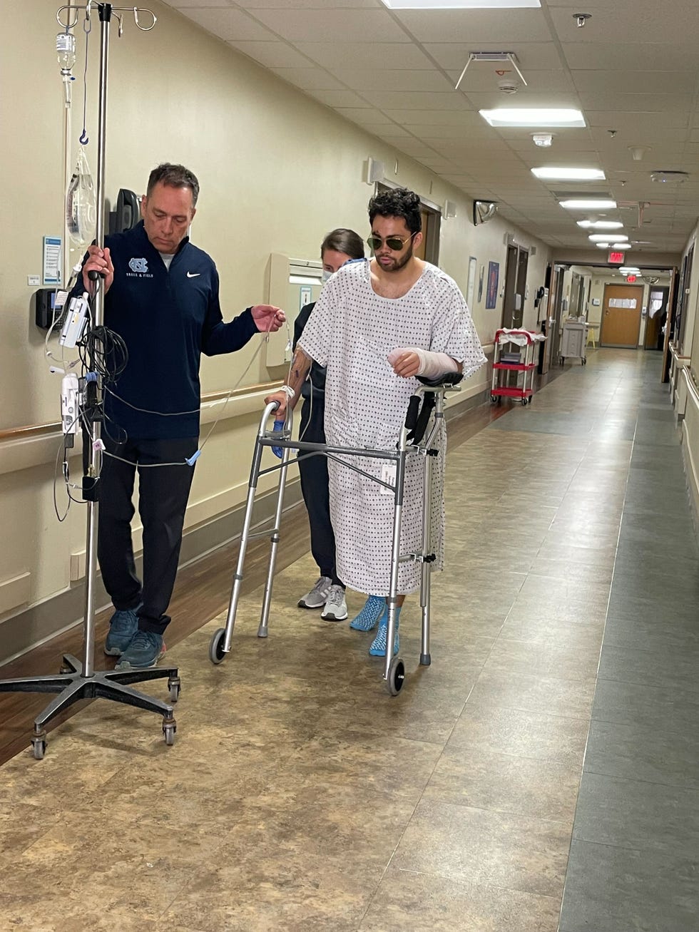 patient assisted with a walker in a hospital corridor