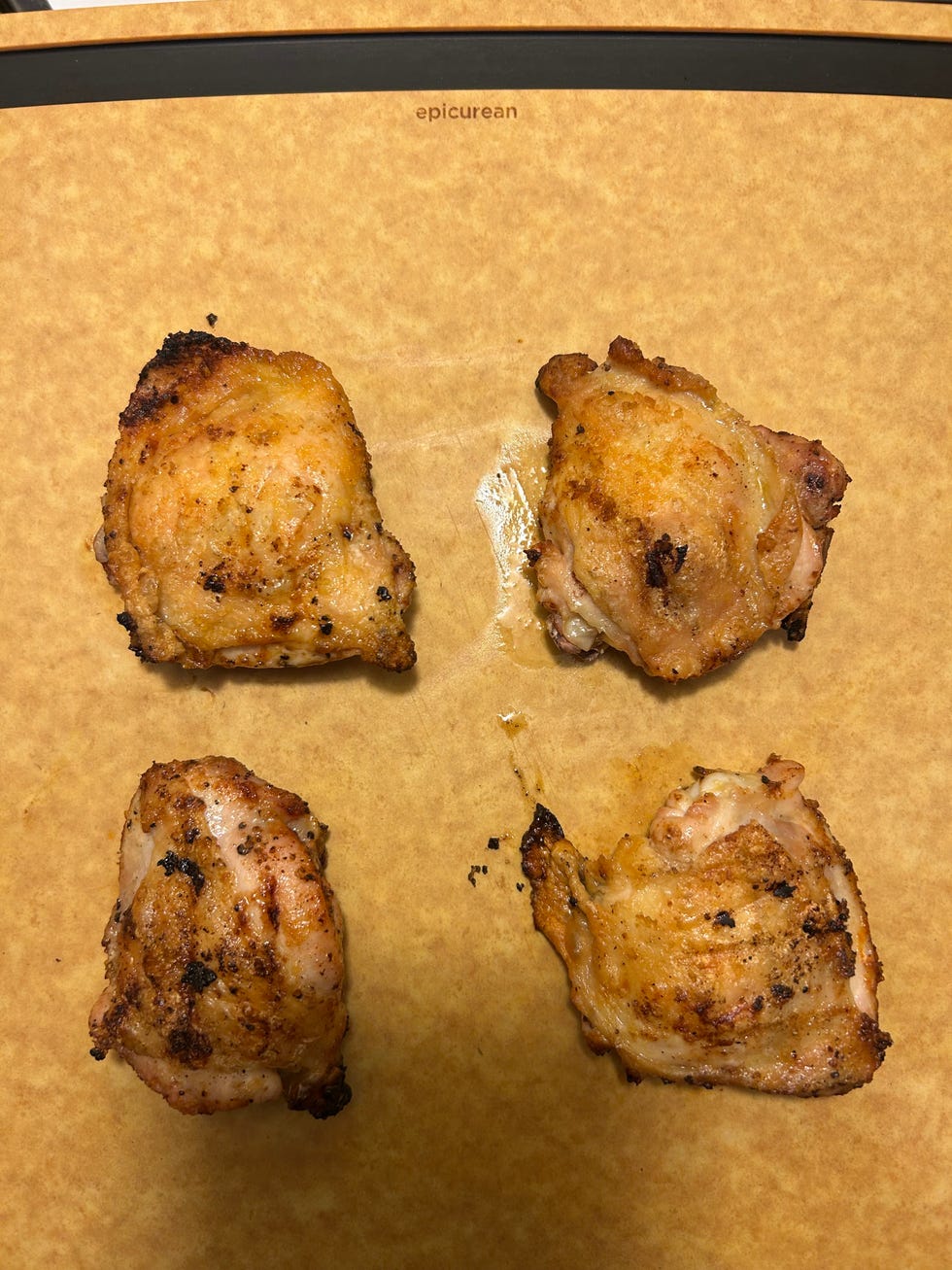 four cooked chicken thighs on a baking sheet