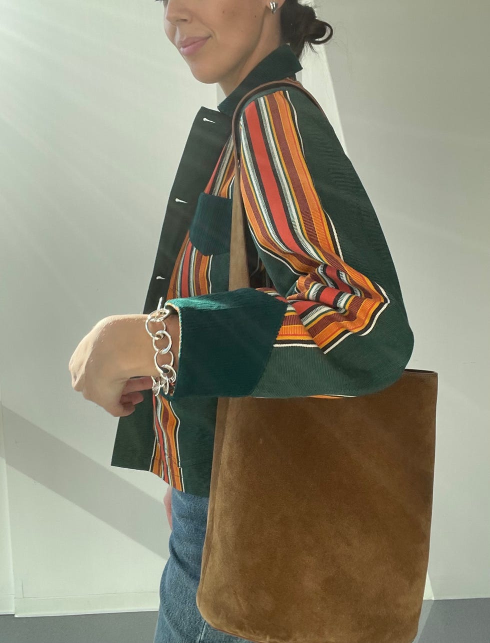 woman wearing a striped shirt and holding a brown suede bag