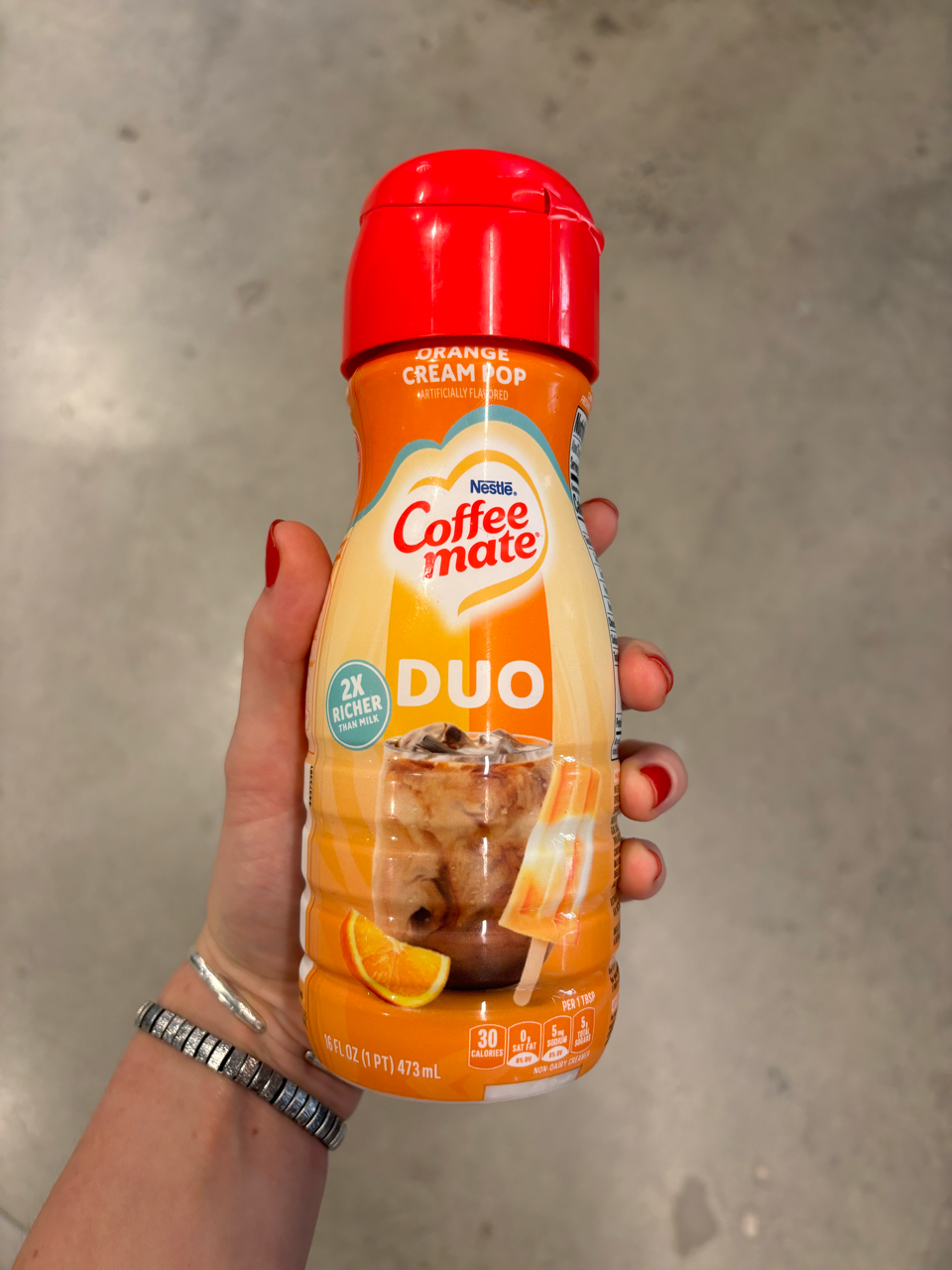 a hand holding a bottle of hot sauce