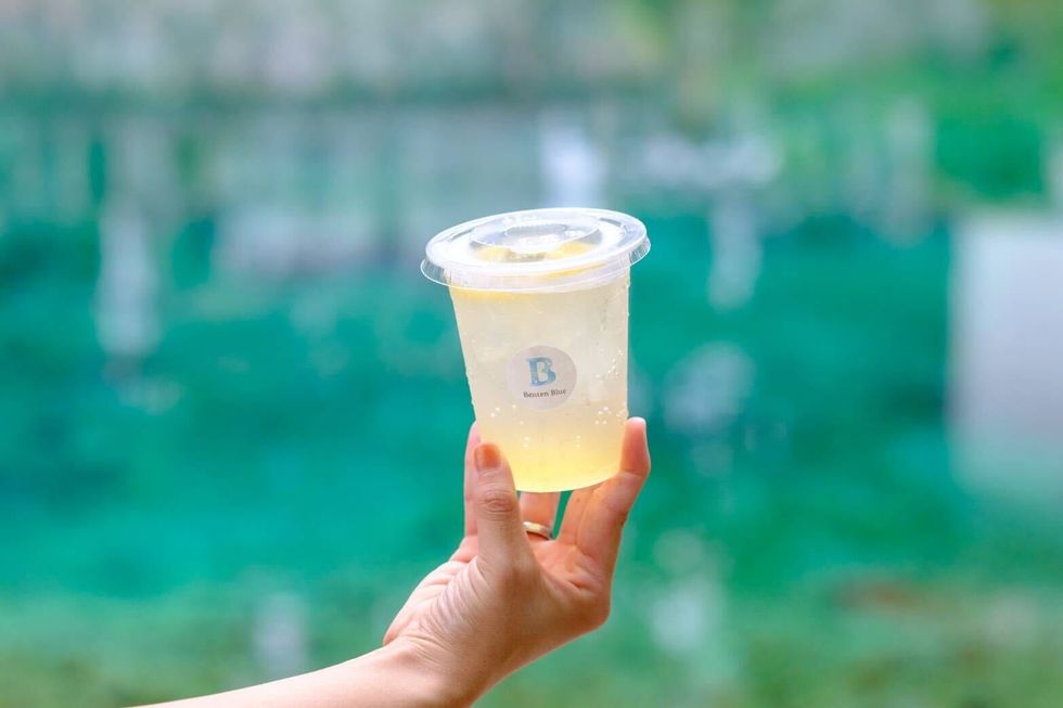 a hand holding a plastic cup with a yellow liquid in it