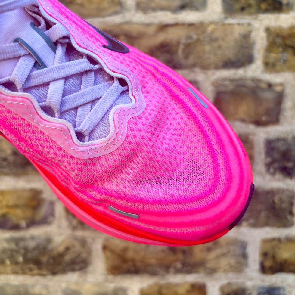 the front of a running shoe against the backdrop of a brick wall