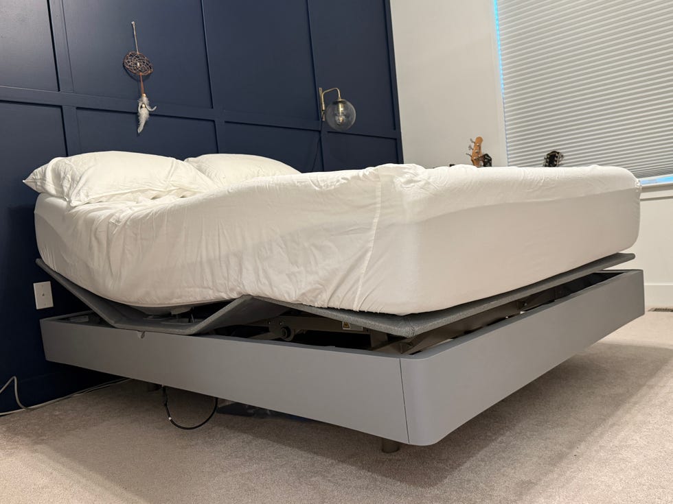 a gray adjustable bed in an elevated position with a mattress on top