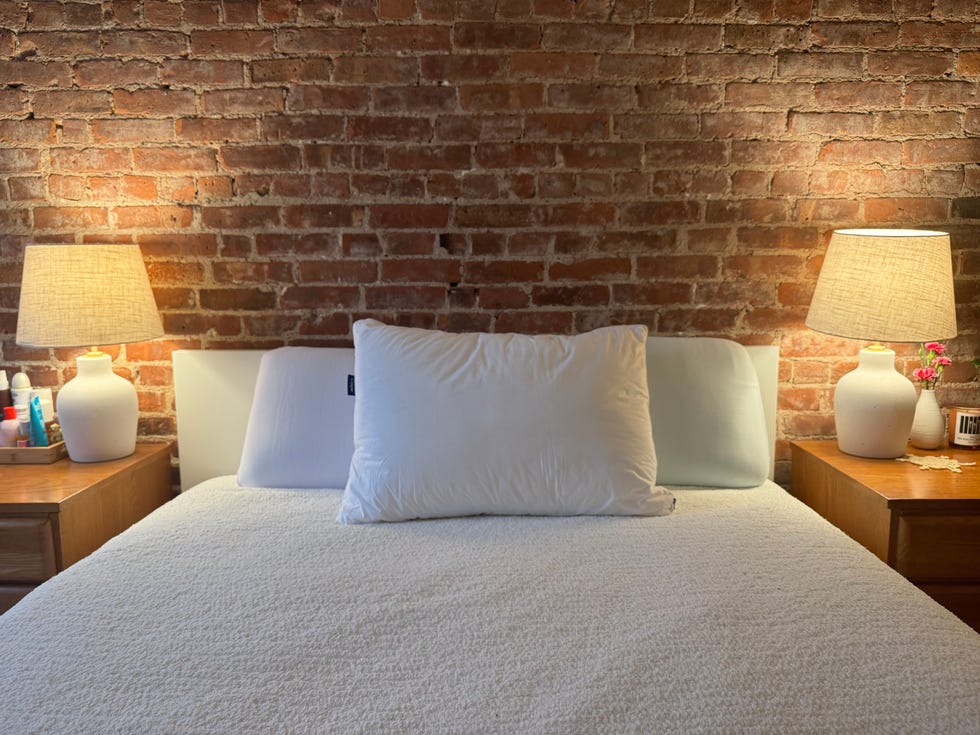 a white bed with pillows with a brick wall background