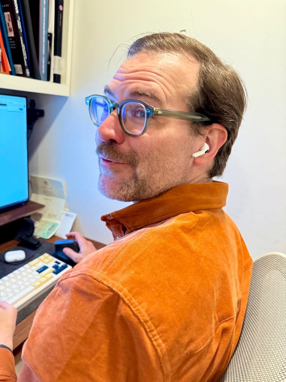 A man wearing Air pods pro 2 at his desk