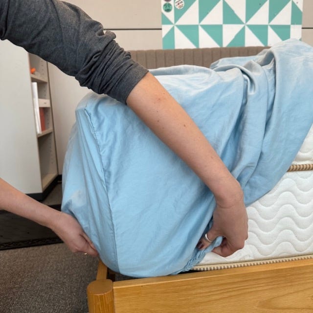 a person putting a fitted sheet onto a mattress