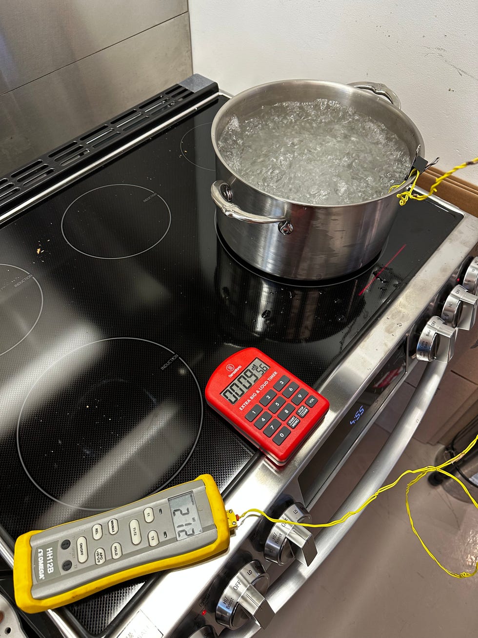 pot of boiling water on a kitchen stove with temperature measurement tool and timer
