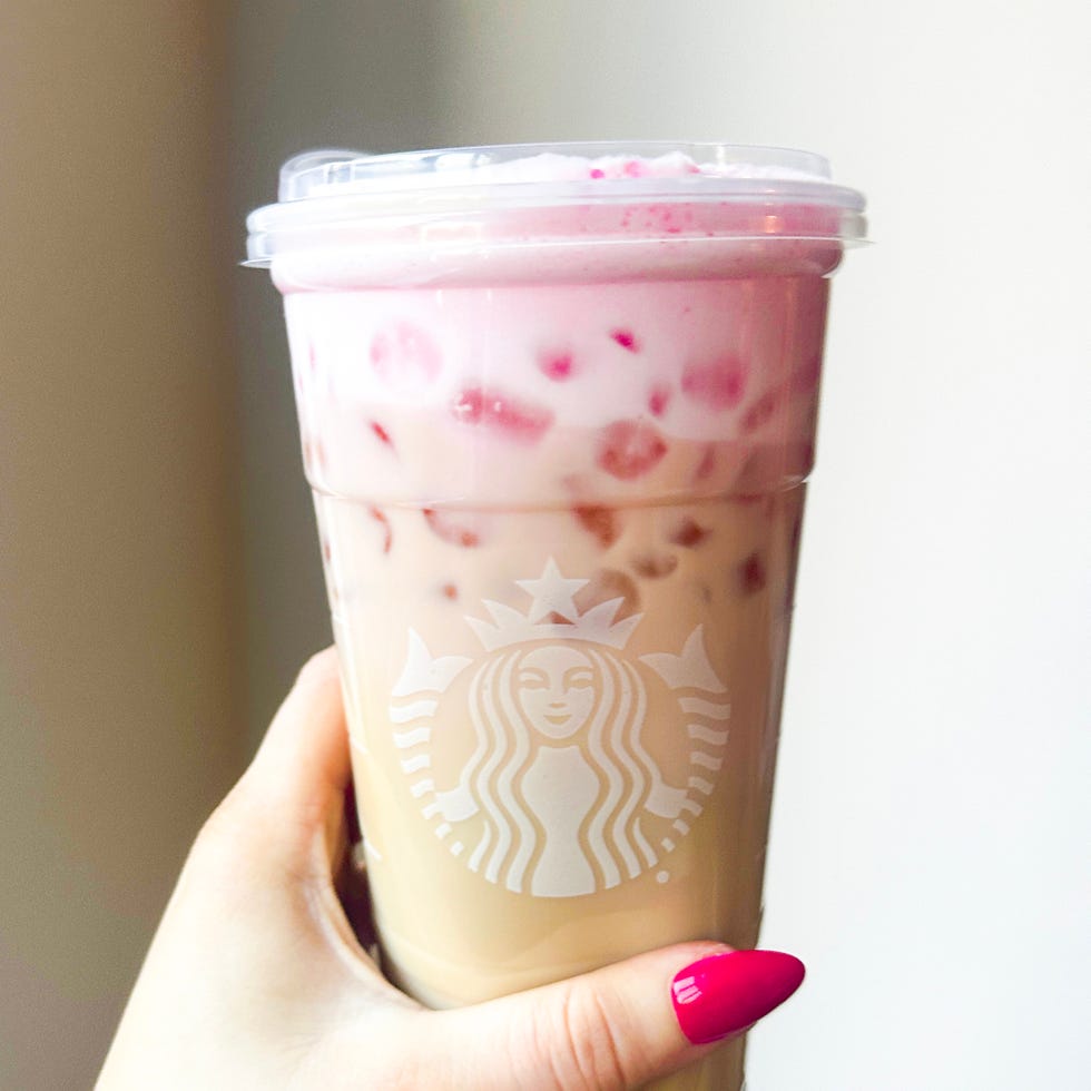 a hand holding a twotoned iced beverage with a branded cup