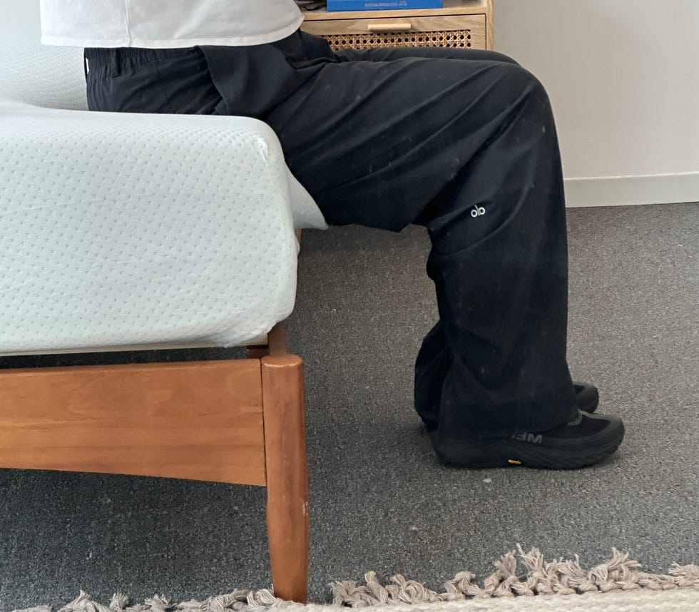a person sits on the edge of a mattress with the edges caving in