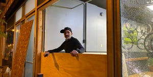 bicycle therapy owner lee rogers stands in the broken window of his storefront