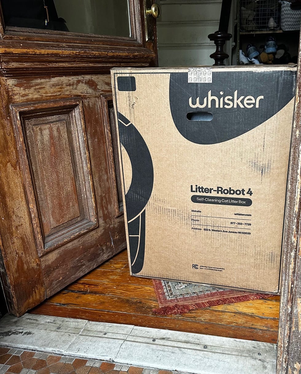 a box containing the litter robot 4 inside a doorway, part of a review of the self cleaning litter box