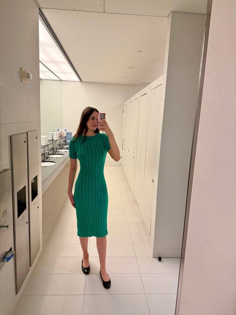 woman wearing a green ribbed dress in a restroom setting