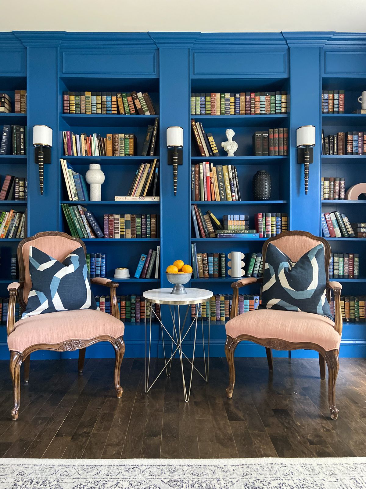 blue library, blue bookcases with books, red reading chairs, black and white sconces
