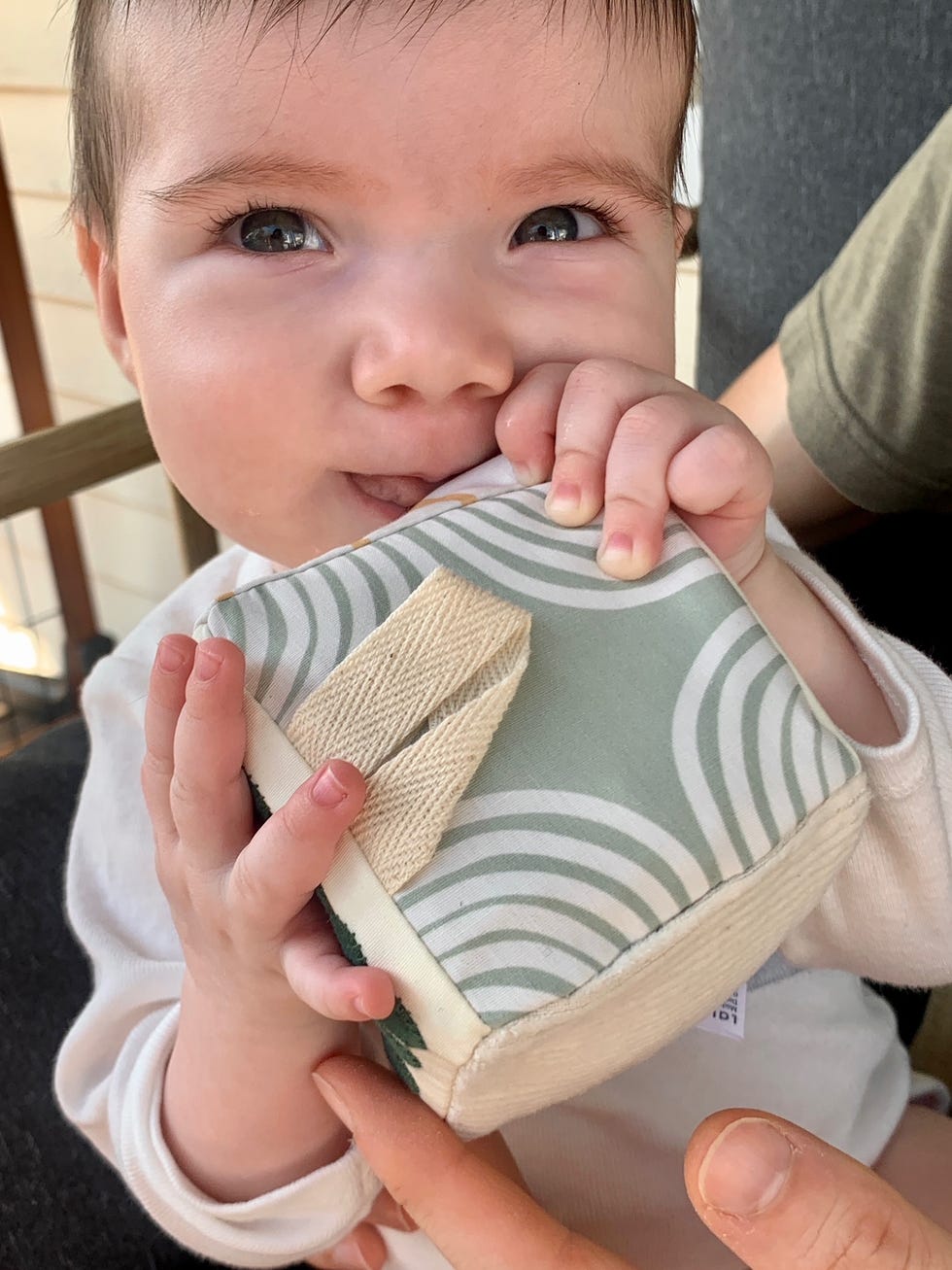 a baby holds a gray and white fabric block, part of the good housekeeping test for the best baby toy subscription boxes