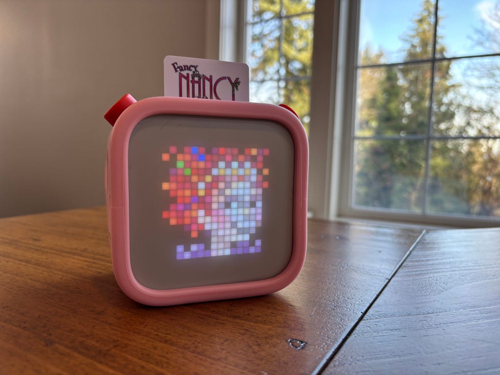 a small pink boxshaped electronic device displaying a colorful pixelated portrait